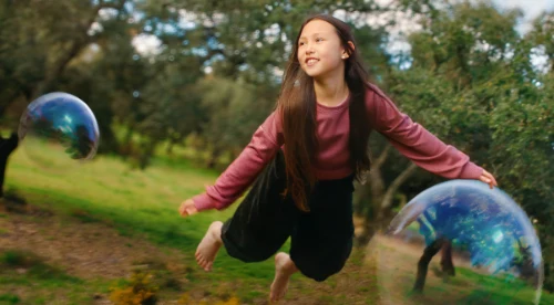 girl flying through the air surrounded by bubbles